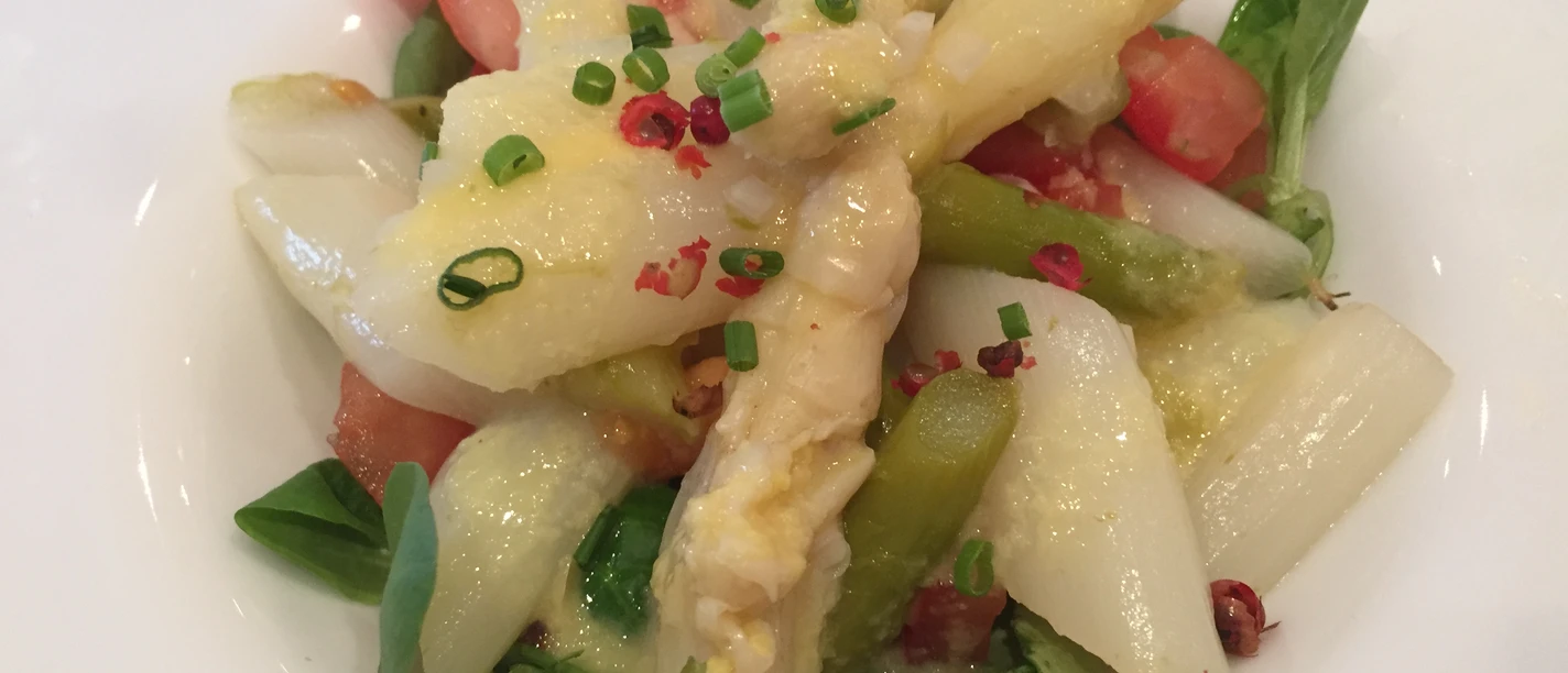 A fresh asparagus dish served with green and white asparagus, tomatoes and chives.