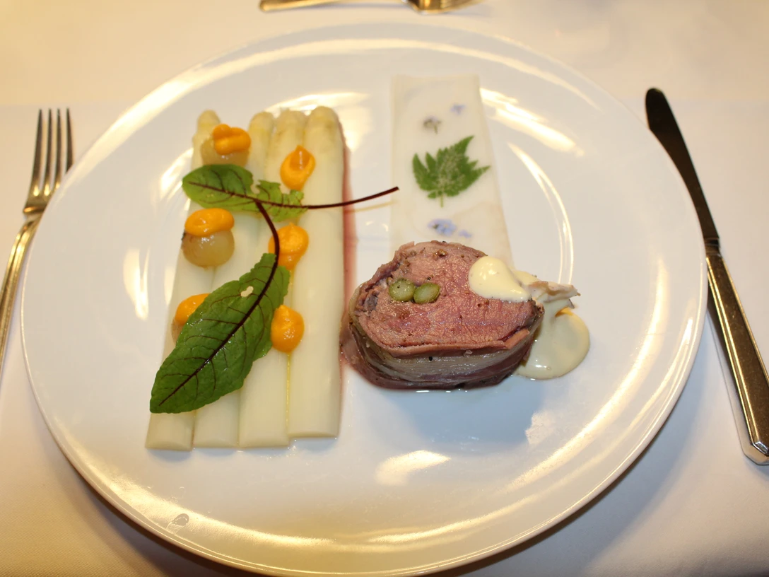 Weiße Spargelstangen mit Sauce und Kräutern, begleitet von einer Fleischroulade auf Teller.White asparagus spears with sauce and herbs, accompanied by a meat roulade on a plate.Hvide asparges med sauce og krydderurter, ledsaget af en kødroulade på en tallerken.Witte aspergesperen met saus en kruiden, vergezeld van een vleesroulade op een bord.
