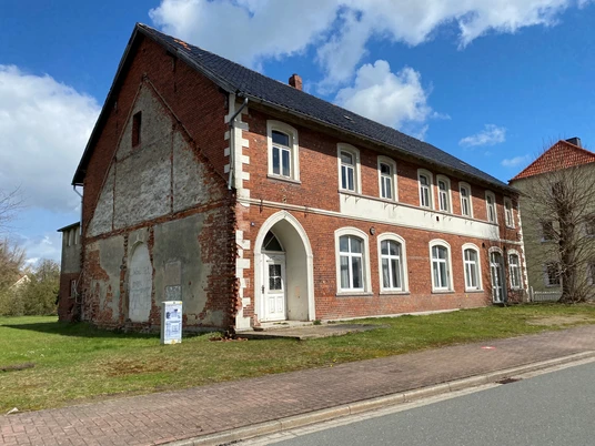 Neues von Uhlenbusch Haus Loccum Backsteinbau mit Spitzbogen und weißen Fenstereinfassungen. Historisches Gebäude an einer Straße.