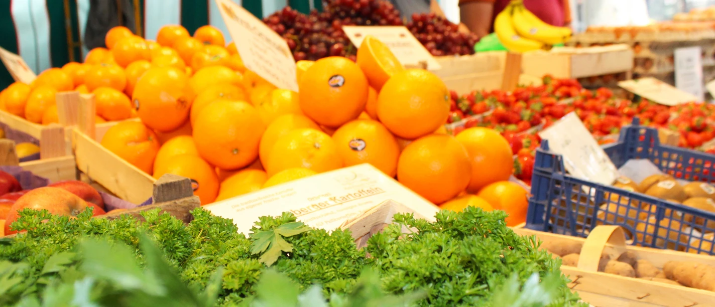 Fresh oranges and juicy strawberries at the weekly market in Stolzenau; fresh herbs in the foreground.