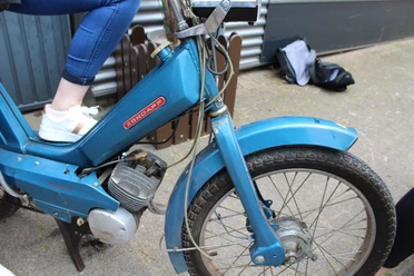 Mofa-Helden Ein blauer Zündapp-Mofa mit Reifenprofil, auf dem eine Person mit weißen Sneakern sitzt.