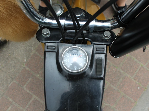 Tacho eines klassischen Mofas zeigt 50 km/h, umgeben von glänzenden Lenkerstangen und Pelzdetails.