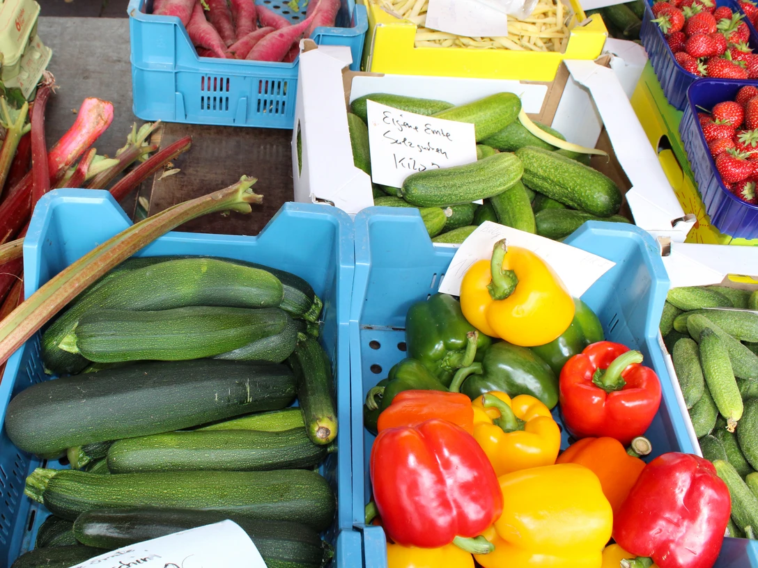 Frisches Obst und Gemüse auf einem belebten Marktstand mit Zucchini, Paprika und Erdbeeren.Fresh fruit and vegetables on a busy market stall with zucchinis, peppers and strawberries.Frisk frugt og grønt i en travl markedsbod med courgetter, peberfrugter og jordbær.Vers fruit en groenten op een drukke marktkraam met courgettes, paprika's en aardbeien.