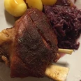 Haxe Knusprige Schweinshaxe mit goldbrauner Kruste, serviert mit Kartoffeln und Rotkohl auf weißem Teller.Crispy pork knuckle with a golden brown crust, served with potatoes and red cabbage on a white plate.Sprød svinekam med en gyldenbrun skorpe, serveret med kartofler og rødkål på en hvid tallerken.Krokante varkensknokkel met een goudbruin korstje, geserveerd met aardappelen en rode kool op een wit bord.