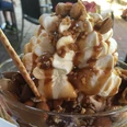 Eisbecher mit Sahne, Karamell, Mandeln, Walnüssen und einer Waffel auf einem Holztisch.Ice cream sundae with cream, caramel, almonds, walnuts and a waffle on a wooden table.Sundae med fløde, karamel, mandler, valnødder og en vaffel på et træbord.Sundae met room, karamel, amandelen, walnoten en een wafel op een houten tafel.