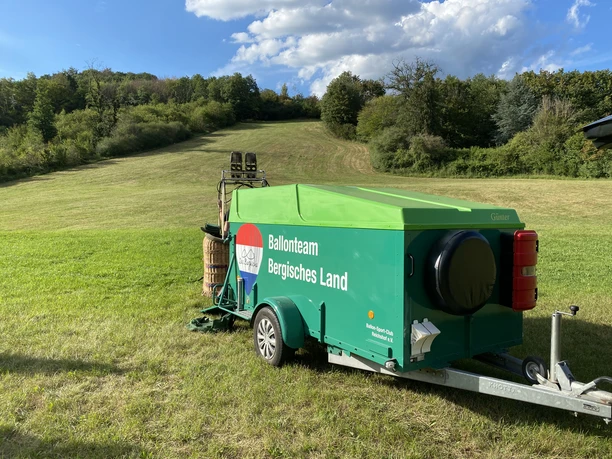 Ballonteam Bergisches Land Grüner Anhänger mit Ballonausrüstung des Ballonteams Bergisches Land auf einer grünen Wiese.