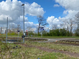 Bahnhof Leese-Stolzenau vor blühenden Bäumen und blauem Himmel; ruhig gelegen mit Bahnsteigzugang.