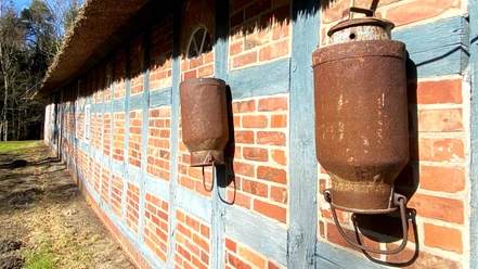 Milchkannen an der Fachwerkmauer vom Moorhof Augustendorf Milchkannen an der Fachwerkmauer vom Moorhof Augustendorf