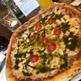 Pizza Pizza auf einem Teller, mit saftigem Käse, frischen Kirschtomaten und grünem Basilikumpesto garniert.