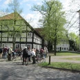 Radfahrende vor dem Heimathaus am Kirchplatz Eine Gruppe von Menschen mit Fahrrädern steht vor historischen Fachwerkhäusern in grüner Umgebung.