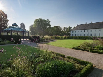 Schloss Benkhausen Schloss Benkhausen steht neben einem gepflegten Garten mit Pavillon unter klarem, strahlendem Himmel.