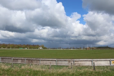 Rennbahn Schwarme Weite grüne Wiese der Rennbahn Schwarme unter einem teilweise bewölkten blauen Himmel.