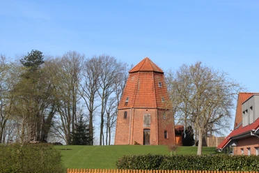 Windmühle Ruine Haßbergen Backsteinruine einer historischen Windmühle umgeben von Bäumen und Wiese unter blauem Himmel.