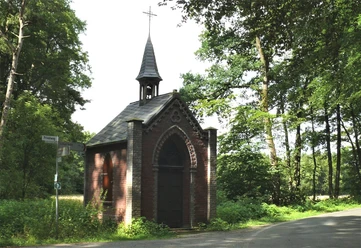 Markuskapelle Eine kleine, historische Kapelle aus Backstein mit spitzem Turm steht umgeben von grünem Wald.