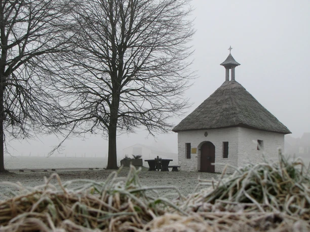 Kapelle "Frauenhäuschen" im Winter Kleine Kapelle mit Strohdach in winterlicher, frostiger Landschaft, umgeben von Bäumen.