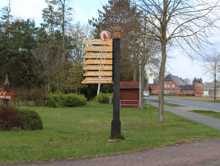 Catucho Wegweiser in ländlicher Umgebung mit verschiedenen Zielangaben, umgeben von Bäumen und Rasenflächen.Signposts in a rural setting with various destinations, surrounded by trees and lawns.Skilte i landlige omgivelser med forskellige destinationer, omgivet af træer og græsplæner.Wegwijzers in een landelijke omgeving met verschillende bestemmingen, omgeven door bomen en gazons.
