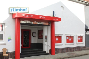 Filmhof Hoya Filmhof Hoya mit roter Fassade und Markise, Kinotafeln, begehbarer Eingang.