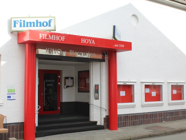 Filmhof Hoya Filmhof Hoya mit roter Fassade und Markise, Kinotafeln, begehbarer Eingang.