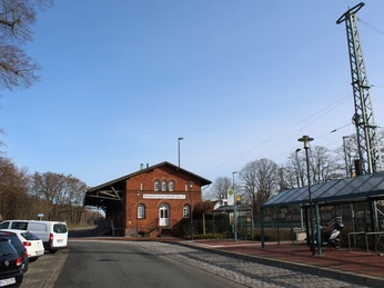 Güterschuppen Eystrup, ein historisches Backsteingebäude nahe einer ruhigen Straße mit parkenden Autos.