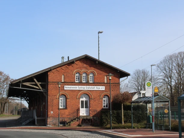 Bahnhof Eystrup Historisches Backsteingebäude des Bahnhofs Eystrup mit markantem Holzdach über den Gleisen.