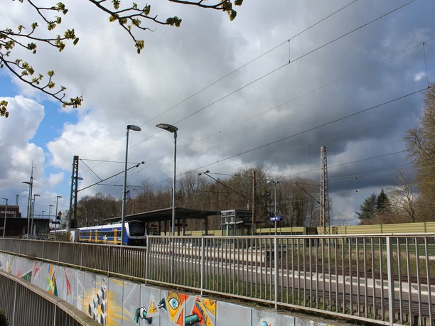 Bahnhof Langwedel Bahnhof Langwedel mit Zug auf Gleis, umgeben von Bäumen und wolkigem Himmel, fotografiert im Frühling.