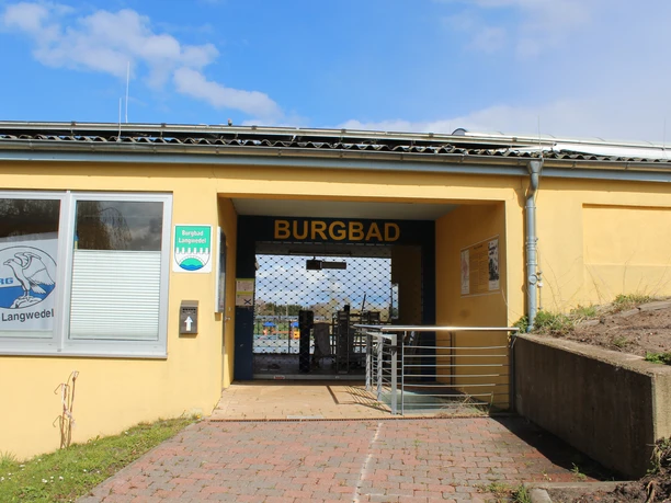 Burgbad Langwedel Eingangsbereich des Burgbads Langwedel mit gelbem Gebäude, Barrierefreiheitshinweis und Tor.