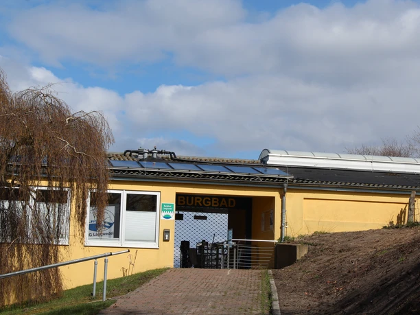 Entrance to the Burgbad Langwedel with a yellow facade; wheelchair accessible thanks to a ramp.