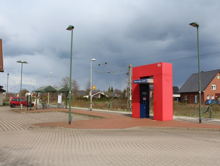 Bahnhof Lahde Bahnhof Lahde mit rotem Infoschalter und teils bewölktem Himmel, umgeben von typischen Gebäuden.
