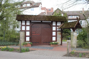 Bad Hopfenberg Historisches Fachwerkhaus mit großen Holztoren, umgeben von Pflanzen und daffodils im Vordergrund.