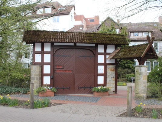 Bad Hopfenberg Historisches Fachwerkhaus mit großen Holztoren, umgeben von Pflanzen und daffodils im Vordergrund.