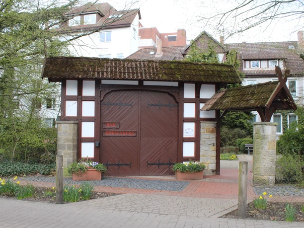 Bad Hopfenberg Historisches Fachwerkhaus mit großen Holztoren, umgeben von Pflanzen und daffodils im Vordergrund.