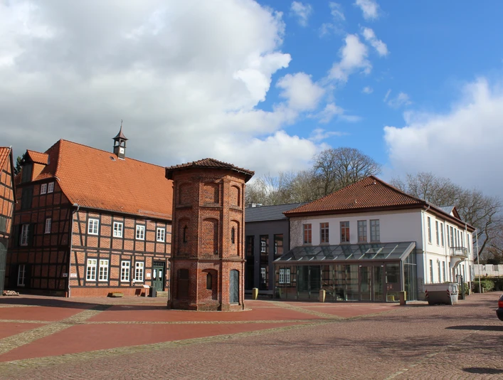 Rathaus Thedinghausen mit Fachwerkbauelementen und prägnantem quadratischem Eckturm bei blauem Himmel.