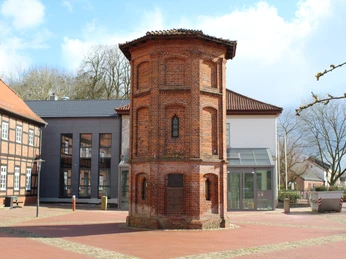 Backstein-Taubenturm vor dem modernen Rathaus Thedinghausen, umgeben von gepflastertem Platz.