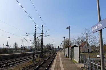 Bahnhof Dörverden mit Bahnsteig, Gleisen, Oberleitungen und Wartehäuschen unter blauem Himmel.