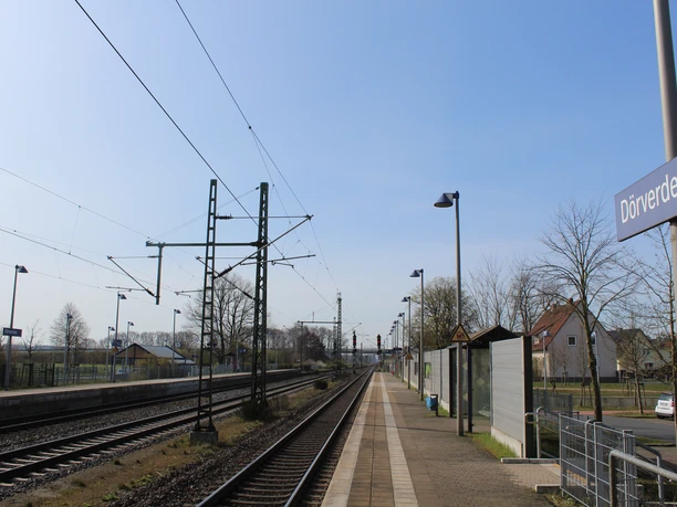 Bahnhof Dörverden mit Bahnsteig, Gleisen, Oberleitungen und Wartehäuschen unter blauem Himmel.