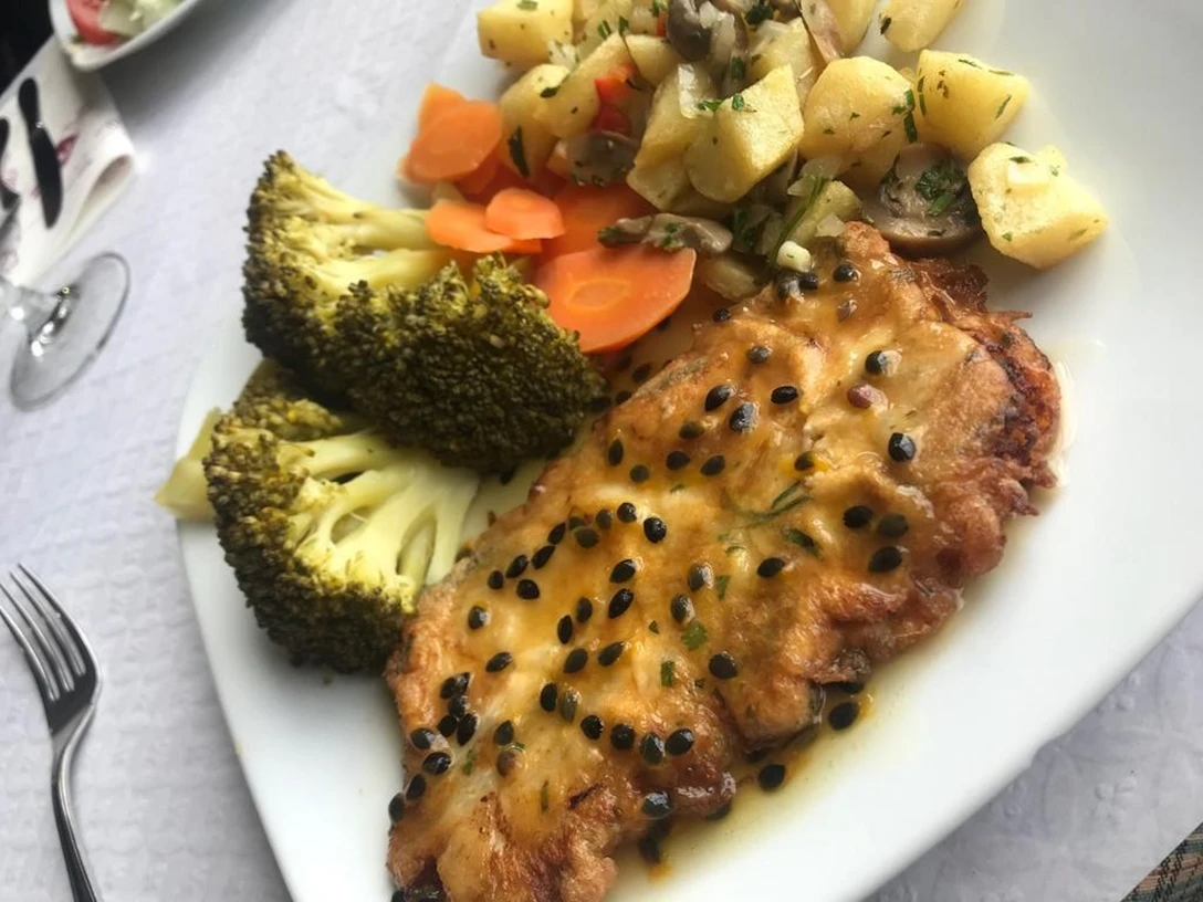 Ein köstlich angerichtetes Fischfilet mit Pfeffersoße, serviert mit Gemüse und Kartoffelwürfeln.
