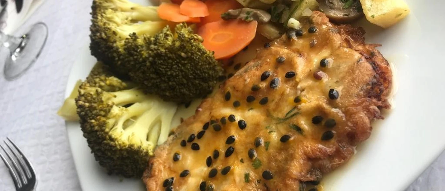 A deliciously prepared fish fillet with pepper sauce, served with vegetables and diced potatoes.