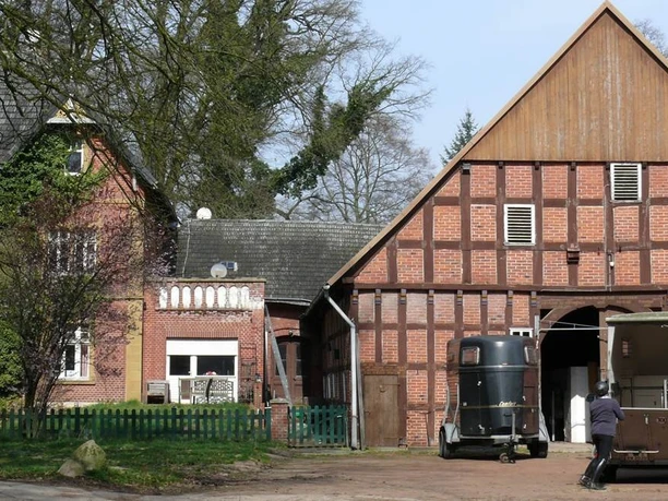 Historische Hofstelle Wester-Ebbinghaus Historischer Gutshof mit zwei roten Backsteingebäuden, Pferdeanhänger und Pferd im Vordergrund.