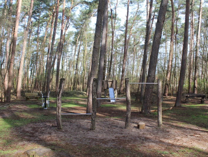 Waldspielplatz Dörverden Ein Waldspielplatz in Dörverden mit turnbaren Holzgeräten zwischen hohen, schlanken Kiefern.