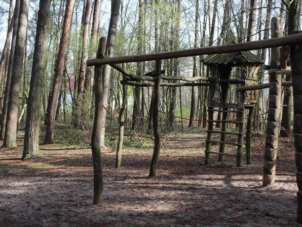 Abenteuerlicher Waldspielplatz in Dörverden mit Klettergerüst aus Holz zwischen hohen Bäumen.