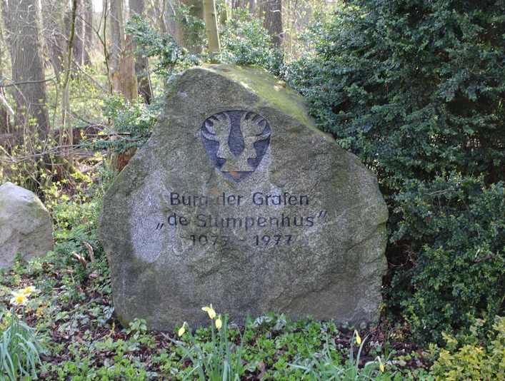 Gedenkstein Grafenburg Wietzen Gedenkstein aus Stein mit Inschrift "Burgen der Grafen de Stumpenhus 1975 - 1977" in einer grünen Waldszene.