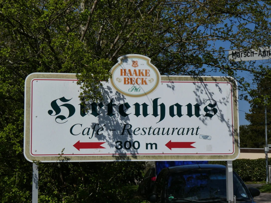 Wegweiser zeigt den Standort des Restaurants Hirtenhaus "Marsch Anna", 300 Meter entfernt, umgeben von Natur.