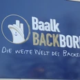 Bäckerei Baalk Baalk Backbord Logo auf blauem Hintergrund mit dem Slogan "Die weite Welt des Backens!".