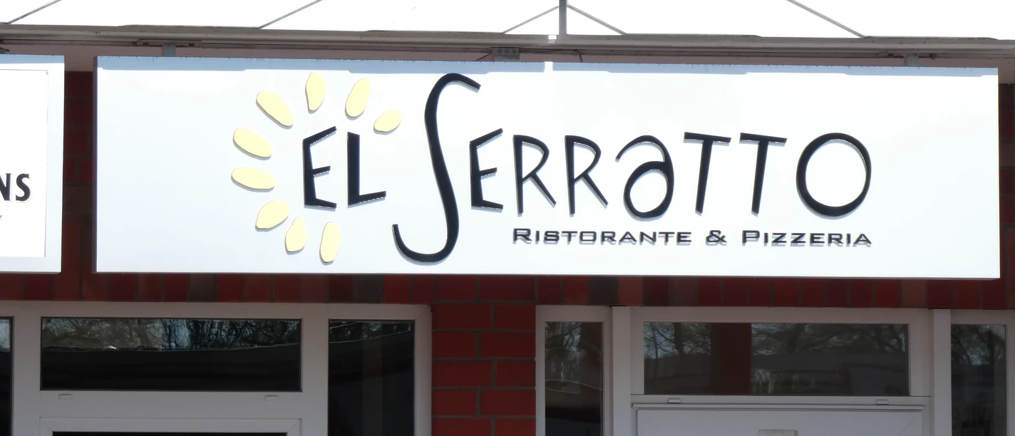 Entrance to a restaurant called "El Serratto", wooden beams and red brick in the façade.