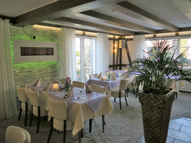 Landhotel Bergischer Hof Ein eleganter Speiseraum mit hellen, gedeckten Tischen und großen Fenstern, die viel Licht hereinlassen.