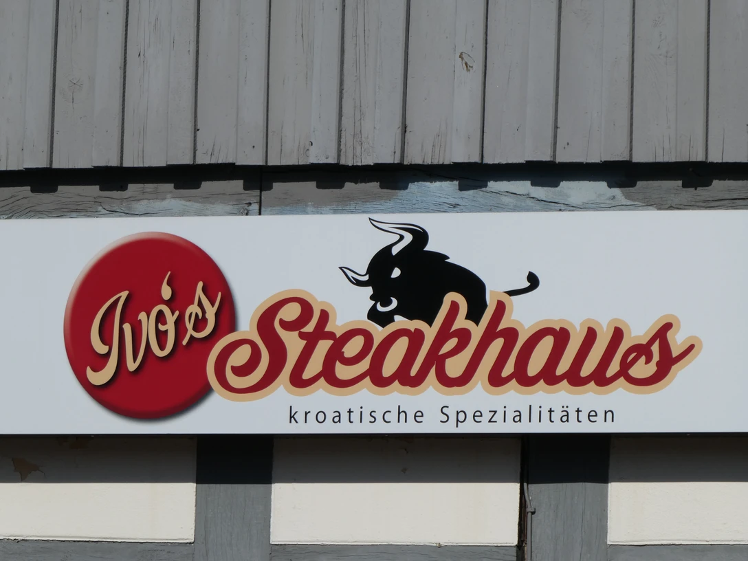 Ivos Steakhaus Das Foto zeigt das Schild von Ivo's Steakhaus mit einem stilisierten Stier und kroatischen Spezialitäten.