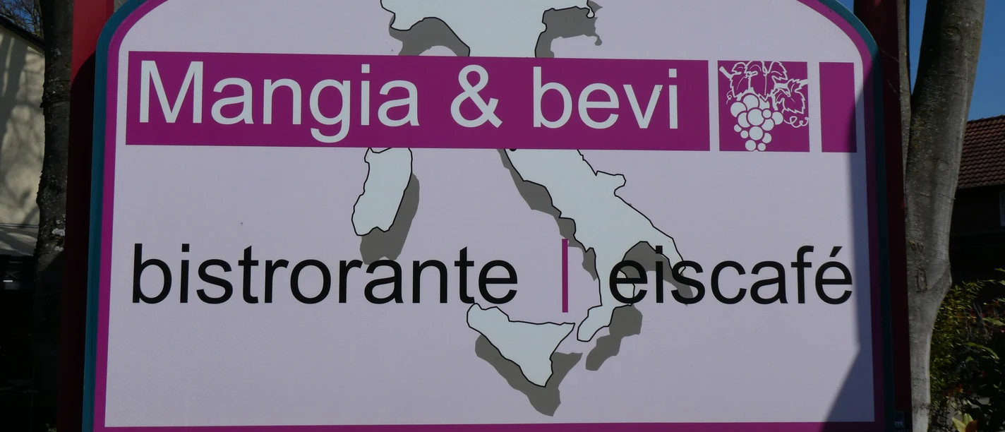Mangia & Bevi bistro sign with map of Italy, wooden frame and foliage-framed background.