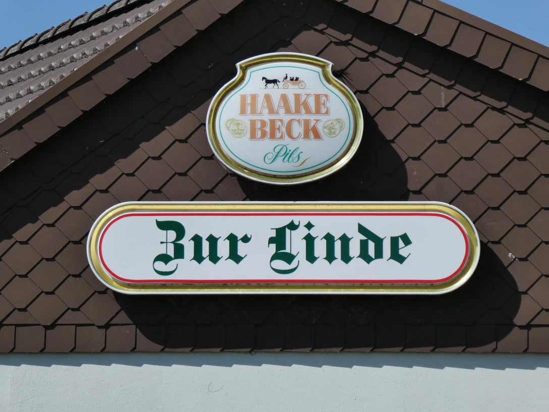 Das Bild zeigt ein Schild des Gasthofs Zur Linde (Meyer-Bierden) mit Haake Beck Pils Logo.