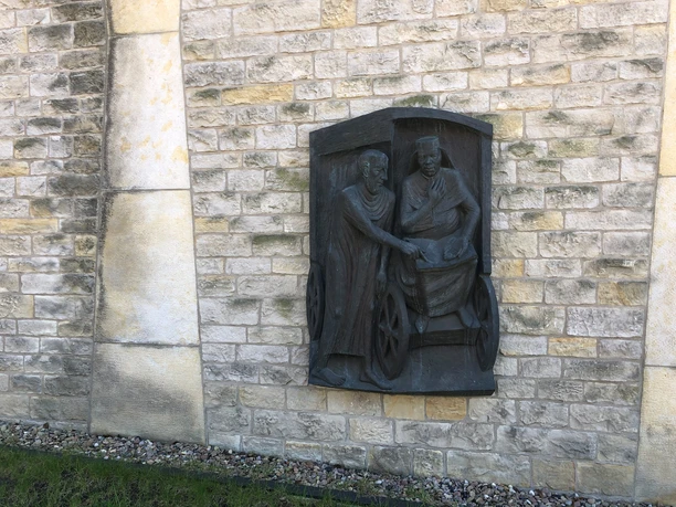 Philipus und der Kämmerer Loccum Relief aus Bronze an einer Steinmauer zeigt zwei Figuren in traditioneller Kleidung beim Händeschütteln.