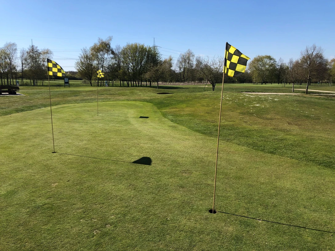 Golfplatz Rehburg-Loccum Aussicht auf einen gepflegten, weitläufigen Golfplatz mit Fahnen, umgeben von Bäumen und blauem Himmel.View of a well-kept, extensive golf course with flags, surrounded by trees and blue sky.Udsigt over en velplejet, stor golfbane med flag, omgivet af træer og blå himmel.Uitzicht op een goed onderhouden, uitgestrekte golfbaan met vlaggen, omringd door bomen en blauwe lucht.